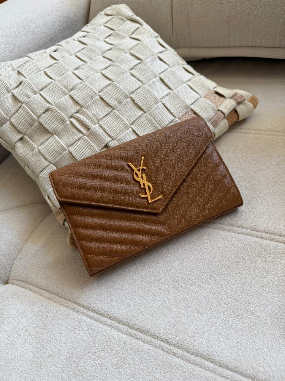Bolsa caramelo com costuras diagonais sobre sofá